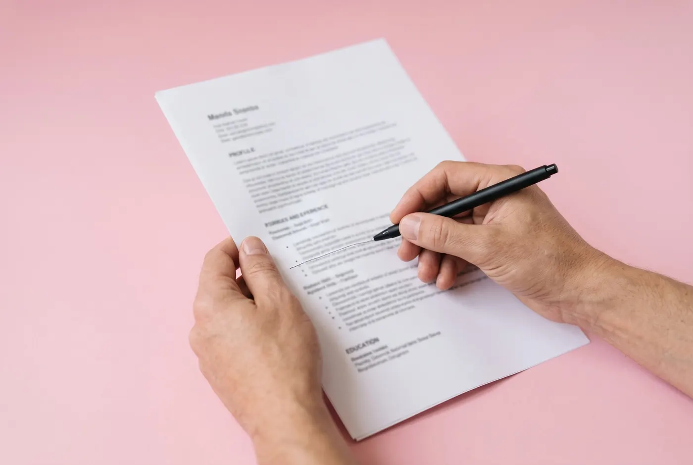 Hands marking a line on a printed CV with a pen